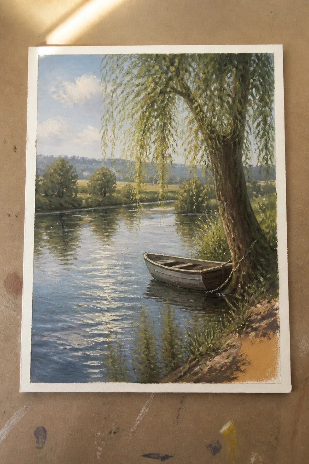 Landscape painting of a rowboat chained to a willow tree by a calm river.