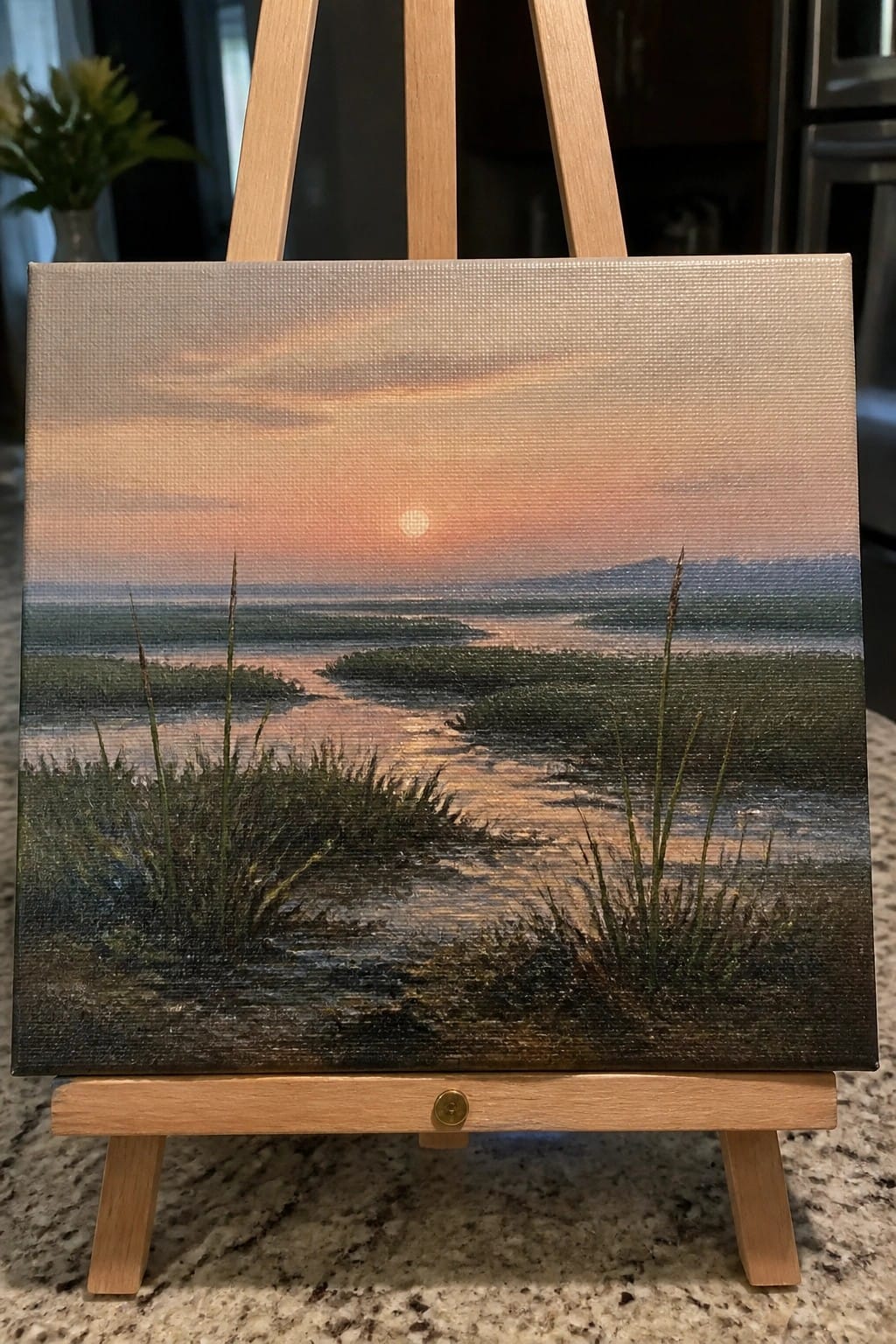 Painting of orange sunset over marshy waters with reeds on wooden easel