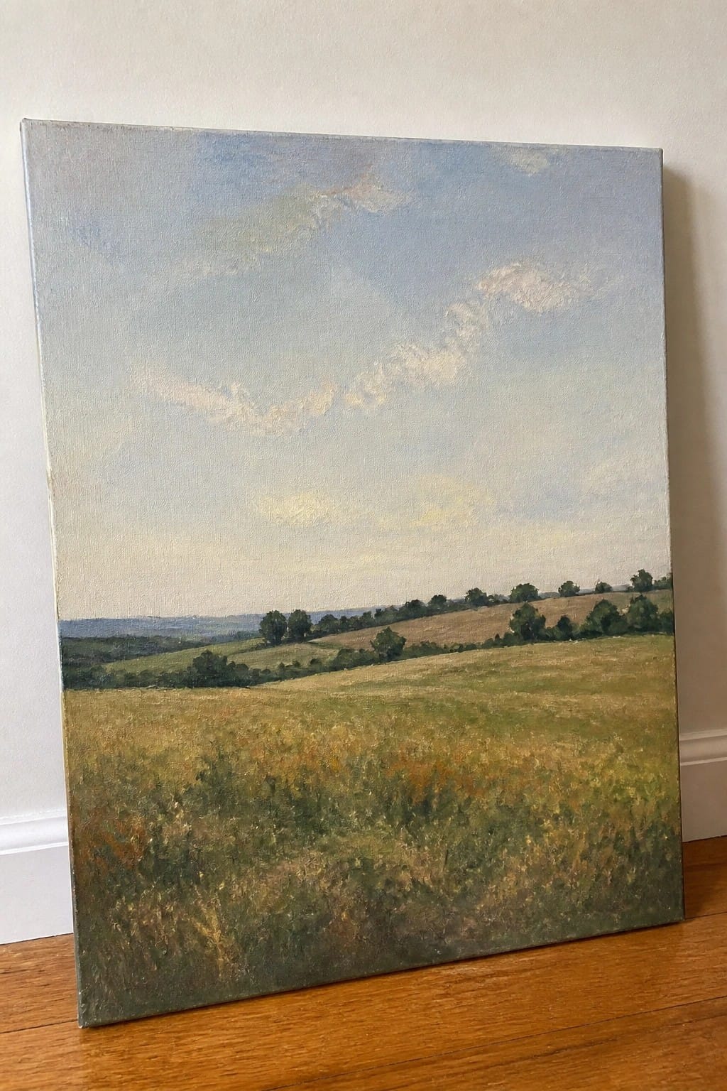 Landscape painting of golden fields, rolling green hills, and cloudy blue sky.