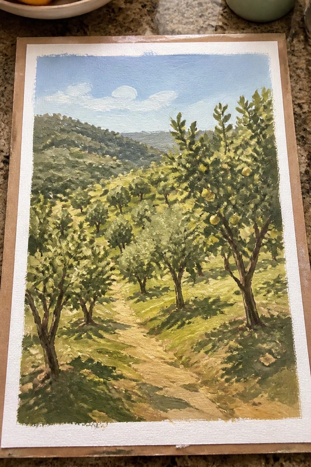Landscape painting of winding path through orchard trees with yellow fruit and green hills.