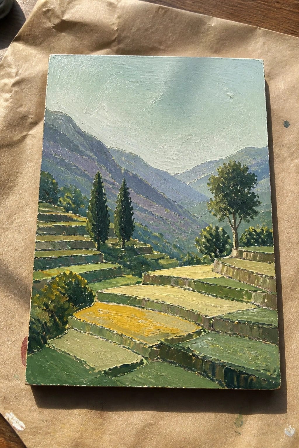 Oil painting of green and yellow terraced fields with cypress trees and misty mountains.