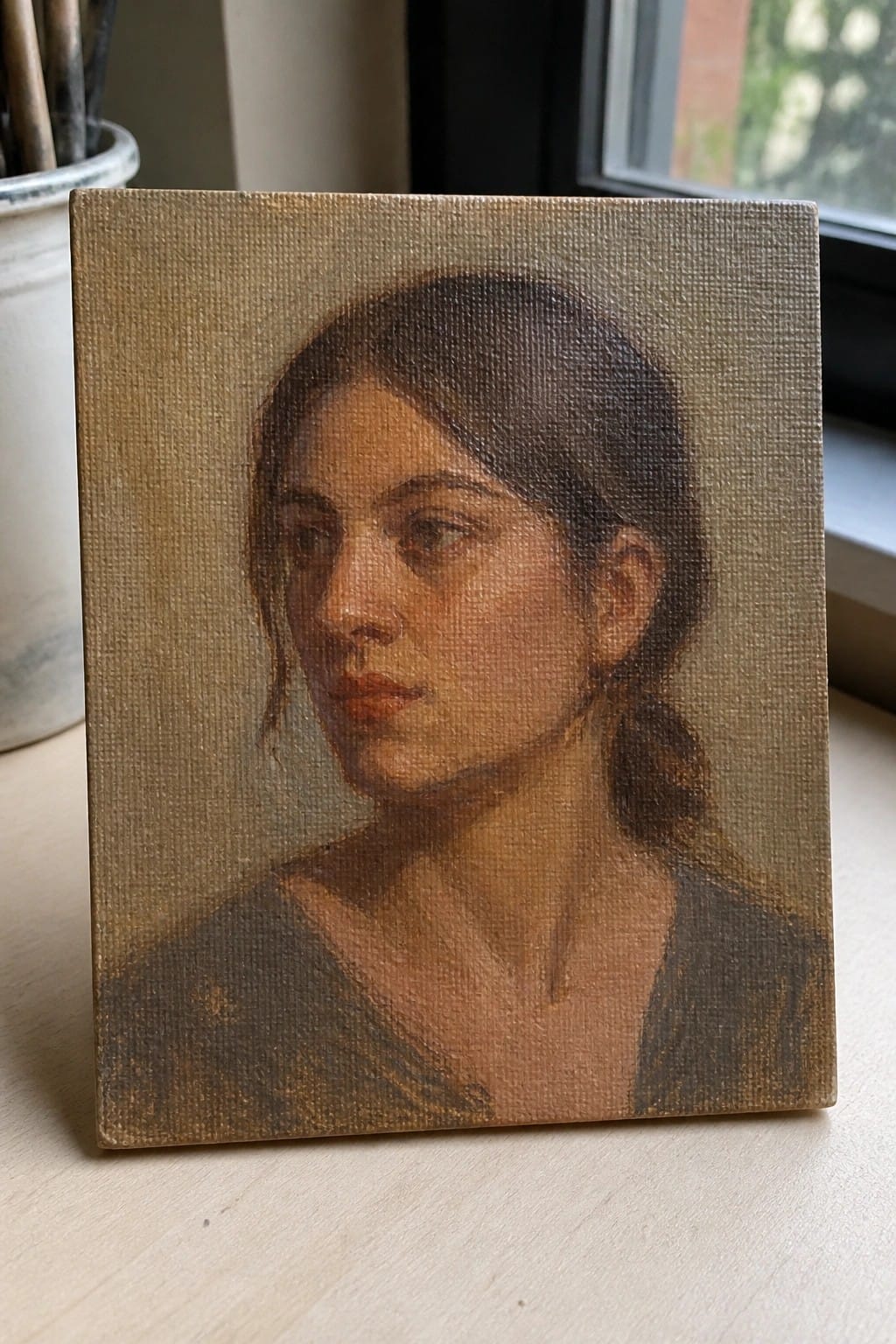 Oil on canvas portrait of a young woman with dark hair in a dark top.