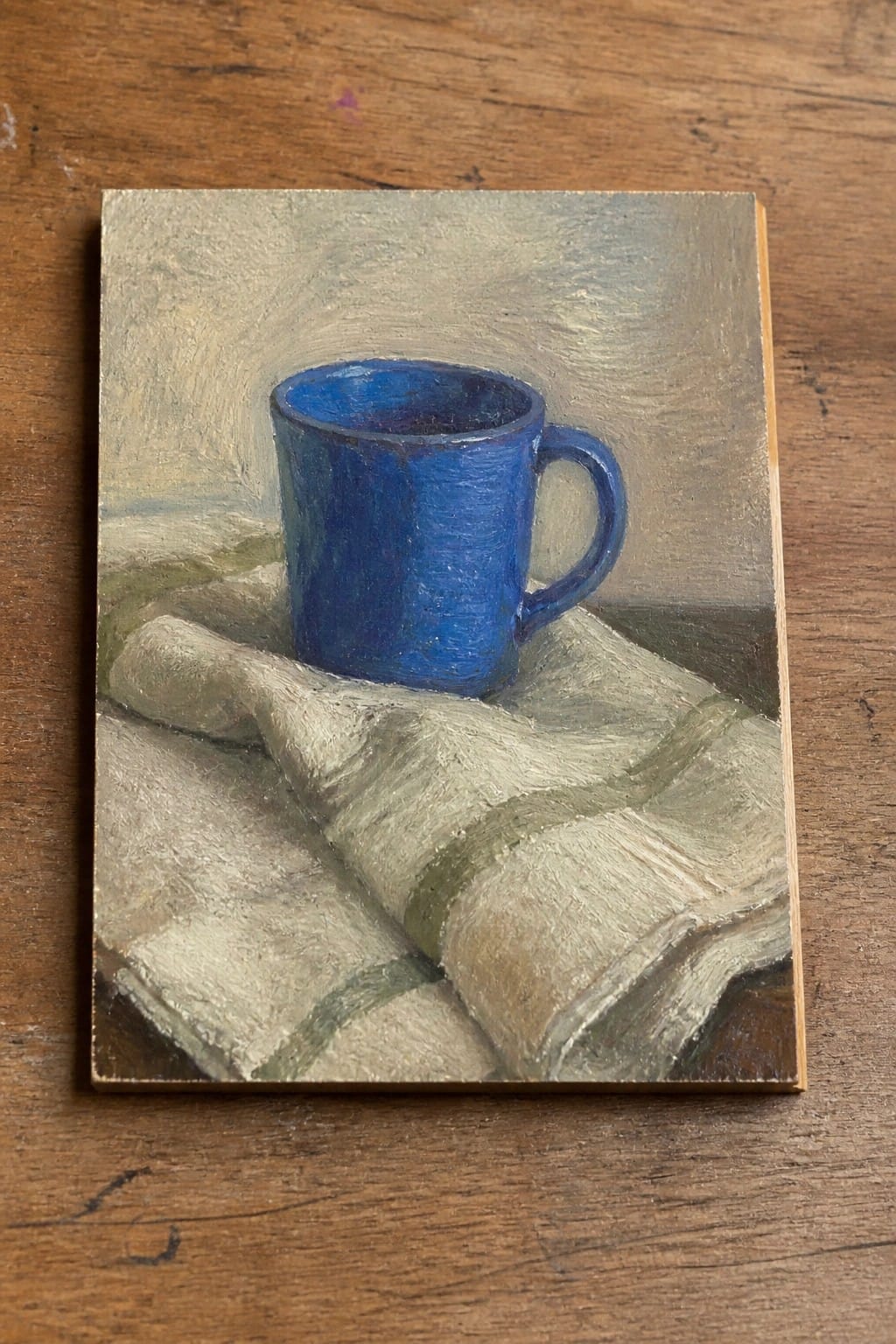 Blue ceramic mug on folded white cloth with green stripes atop wood