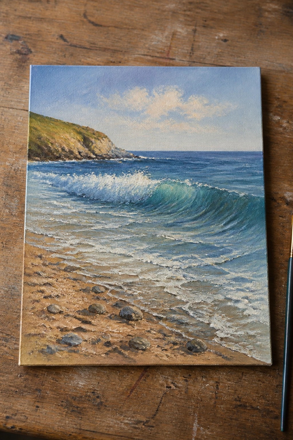 Realistic seascape painting of waves on sandy beach with cliffs and nearby paintbrush.