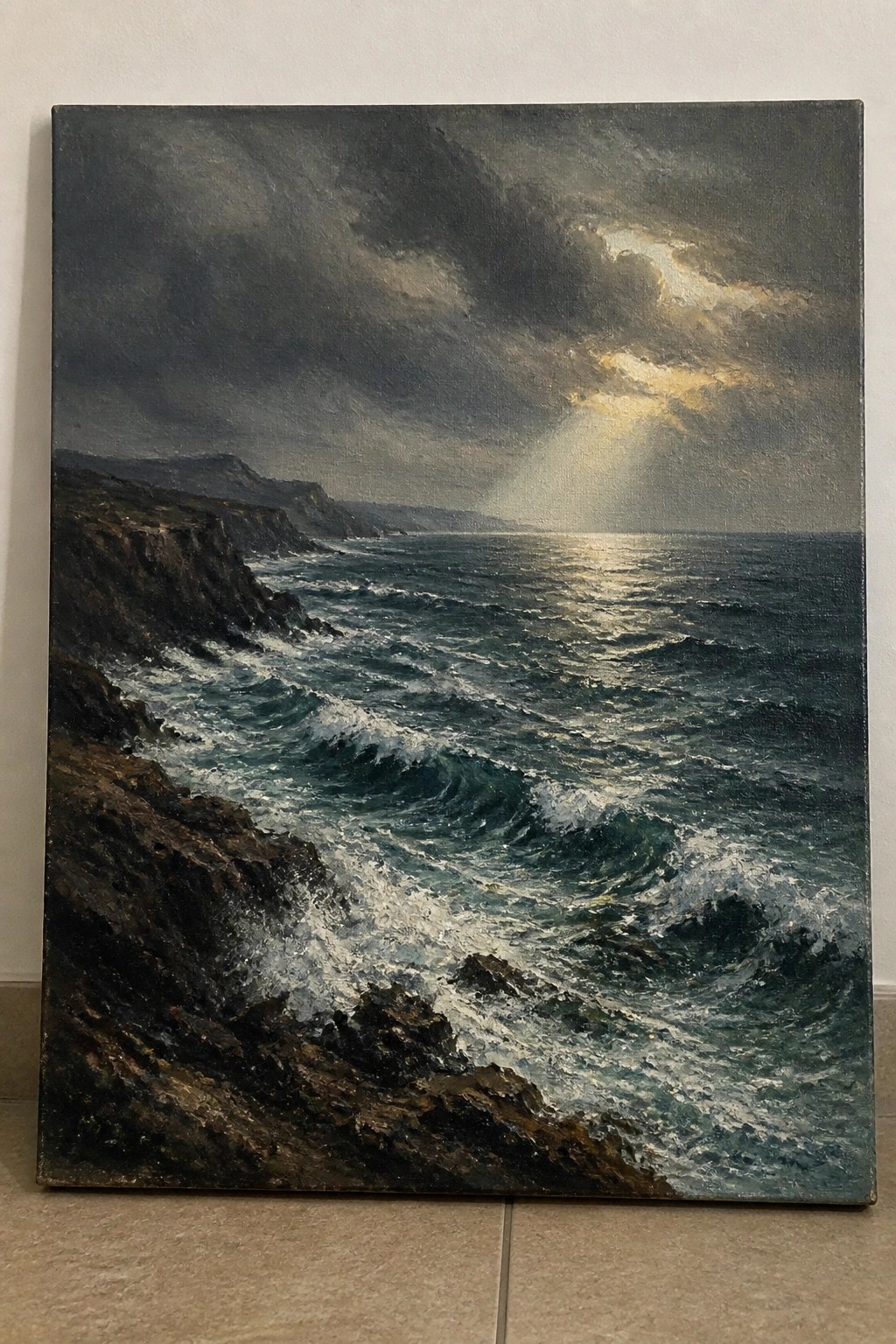 Dramatic seascape painting of waves crashing on rocky cliffs under stormy clouds with sunlight rays.