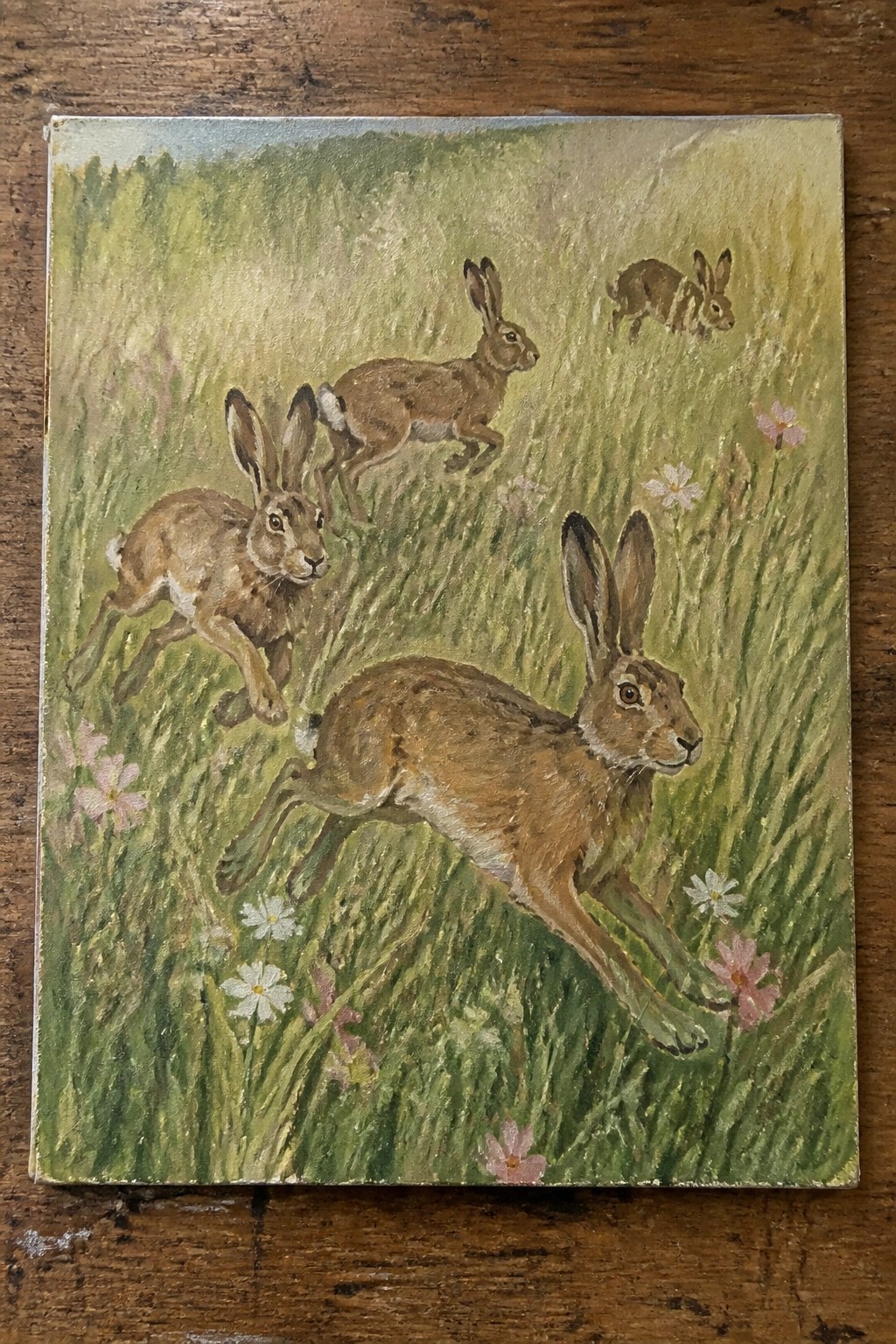 Four brown hares bounding through a wildflower-strewn green meadow in a painting.