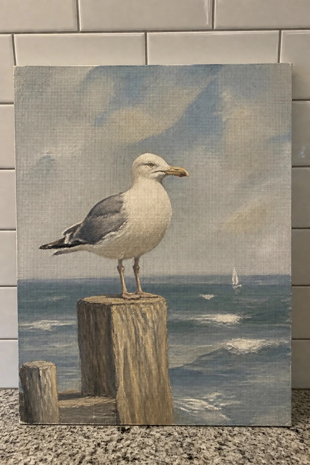 Seagull with white body and gray wings perched on wooden post above ocean
