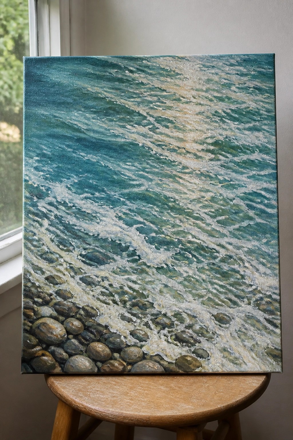 Painting of turquoise waves with white foam approaching a pebble shore on wooden stool
