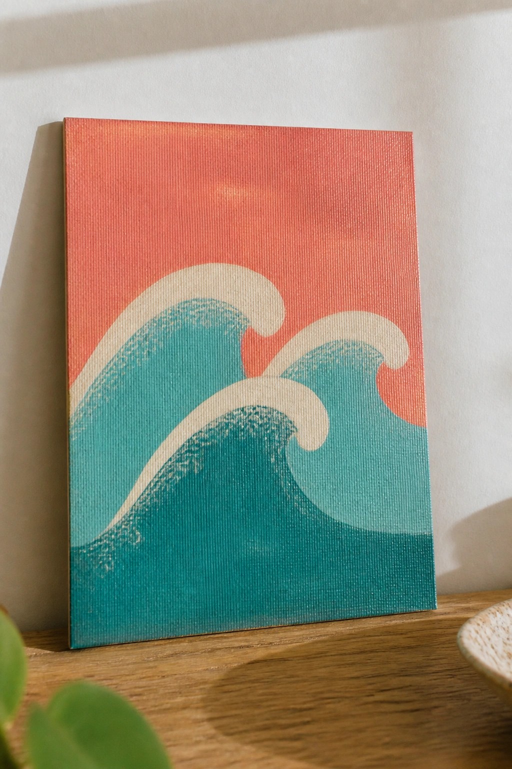 Abstract teal waves with white foam on coral canvas atop wooden table