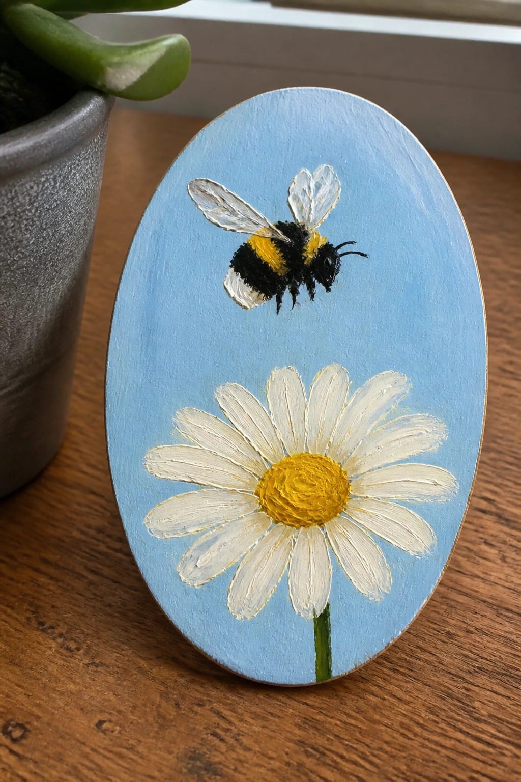 Oval blue plaque with yellow-black bumblebee flying above white daisy flower