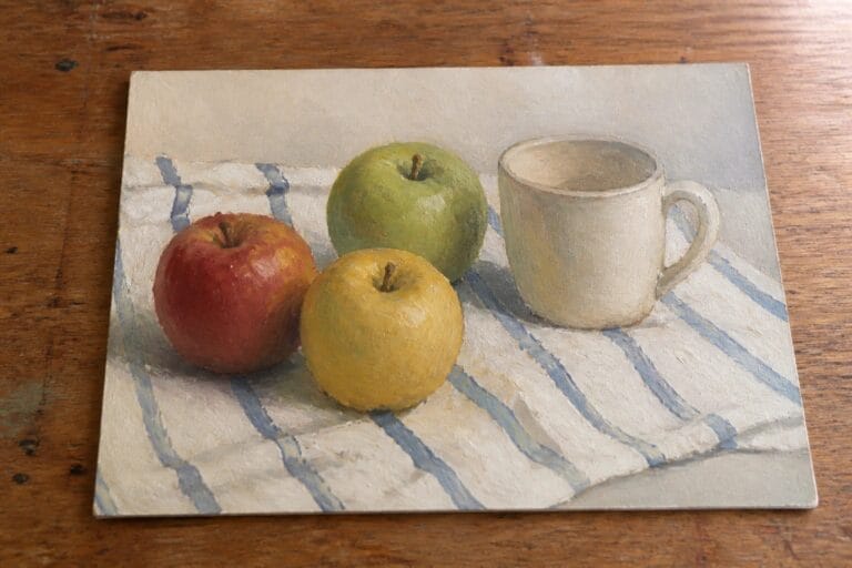 23 Easy Still Life Oil Painting Ideas Centered Around Fruit and Simple Objects Still life painting of three apples and white mug on blue-striped cloth