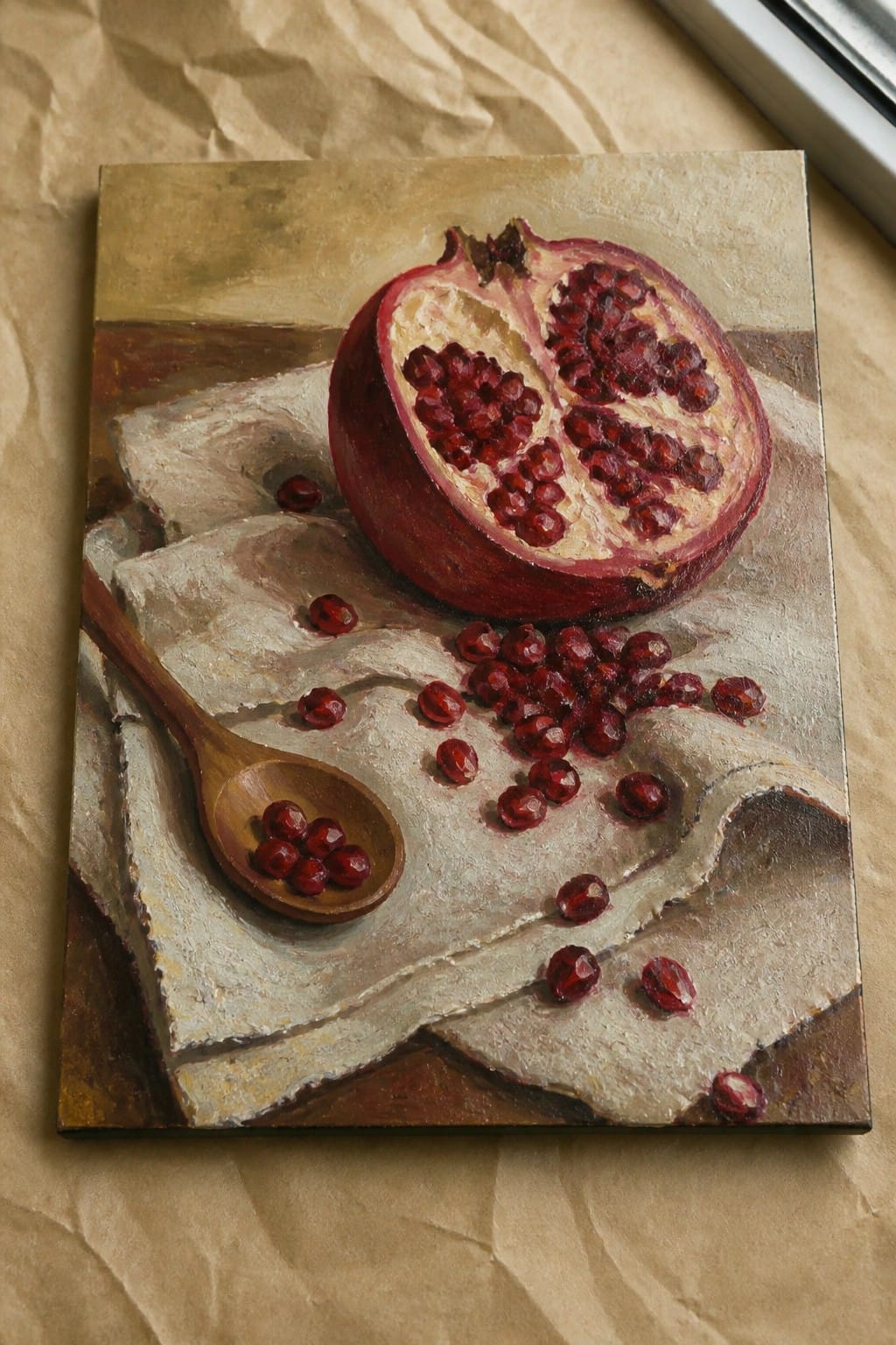 Realistic oil painting of halved pomegranate with red seeds and wooden spoon on cloth