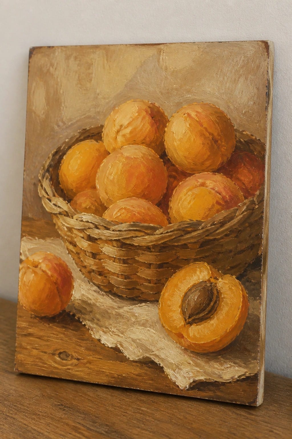 Painting of peaches in a woven basket with one halved on wood.