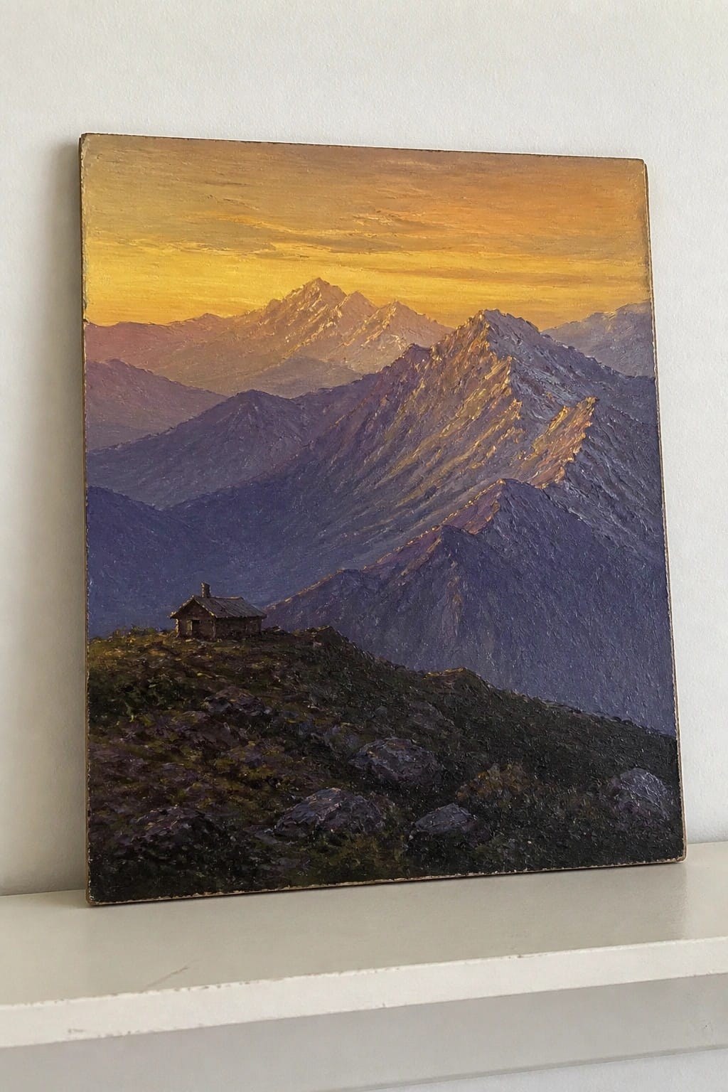 A realistic oil painting of a mountain landscape at sunset with a small wooden cabin on a rocky hill in the foreground and golden light illuminating the distant peaks.