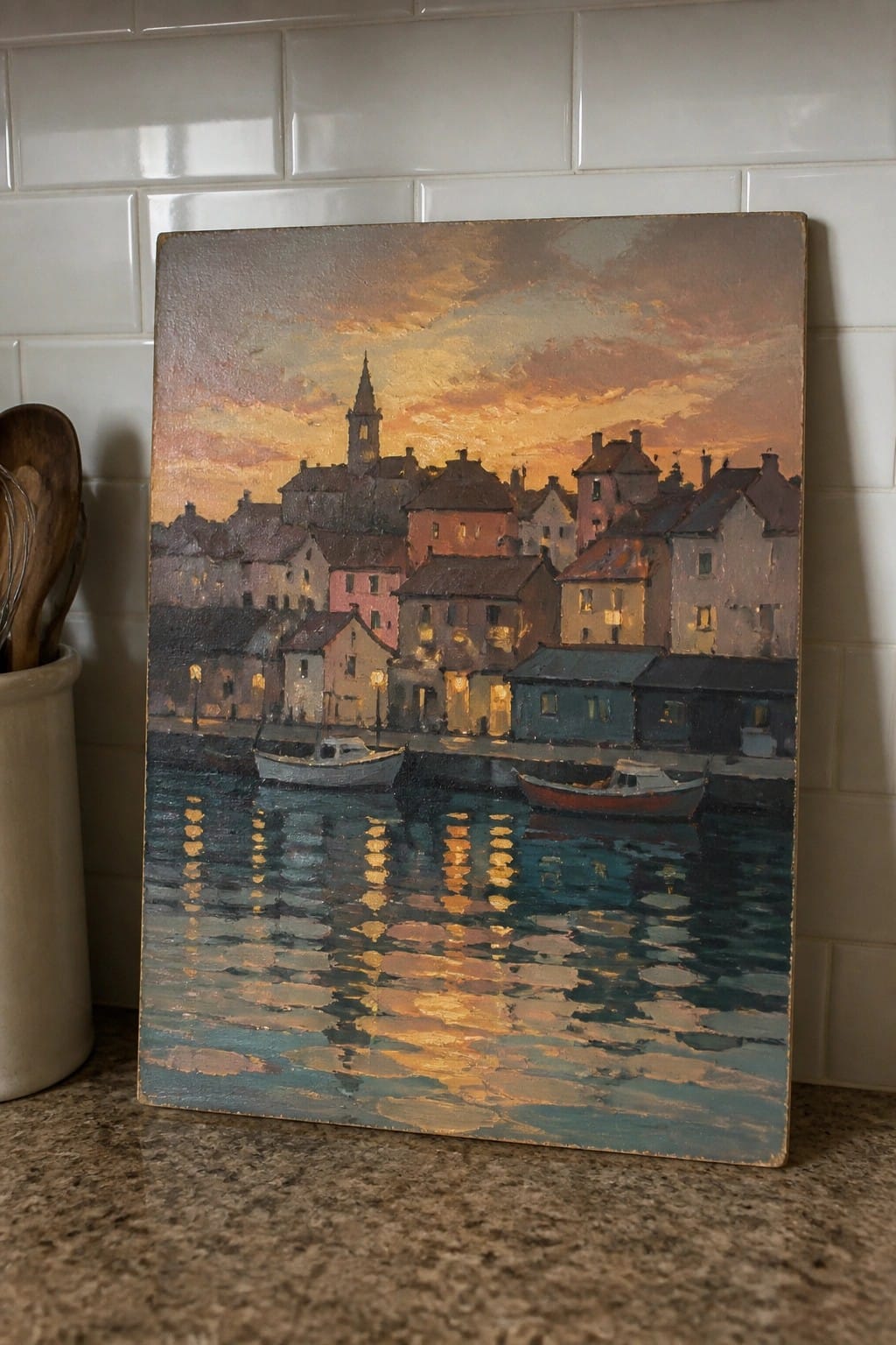 An oil painting of a coastal town at sunset with buildings along the water, boats in the harbor, and glowing reflections on the surface.