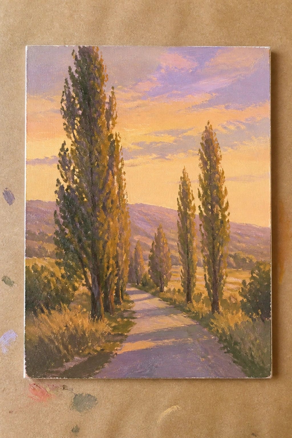 Winding dirt path lined with tall trees beneath vibrant orange and purple sunset sky.