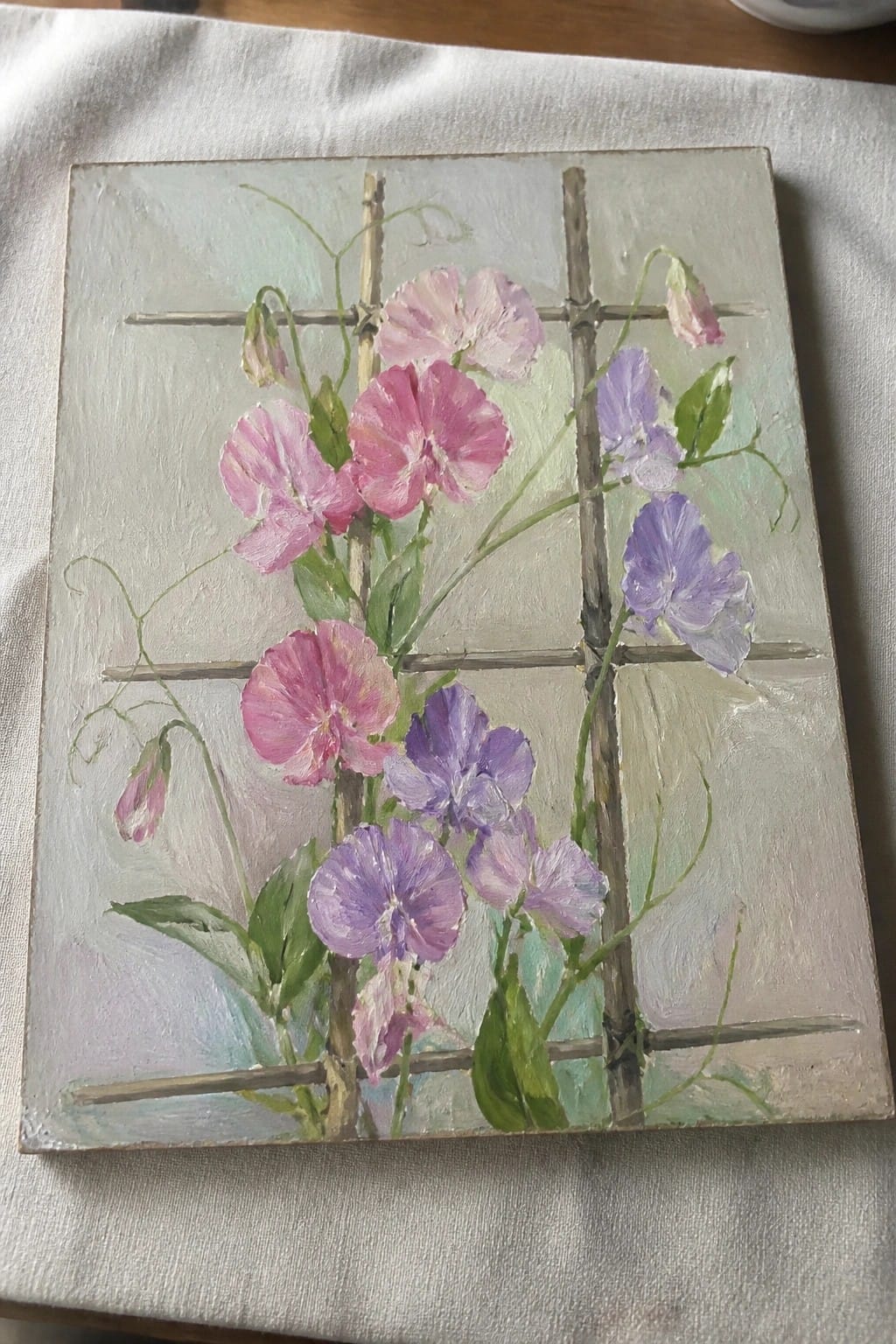 Pink and purple sweet pea flowers climbing wooden trellis with green leaves and vines