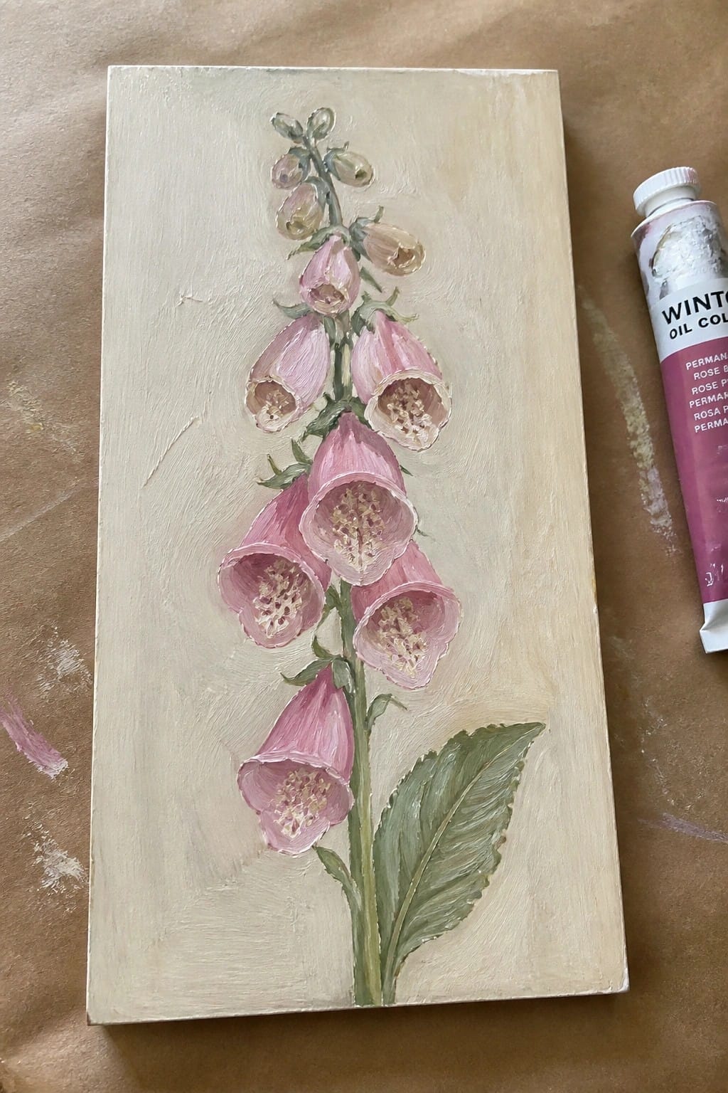 Pink foxglove oil painting on canvas beside permanent rose paint tube