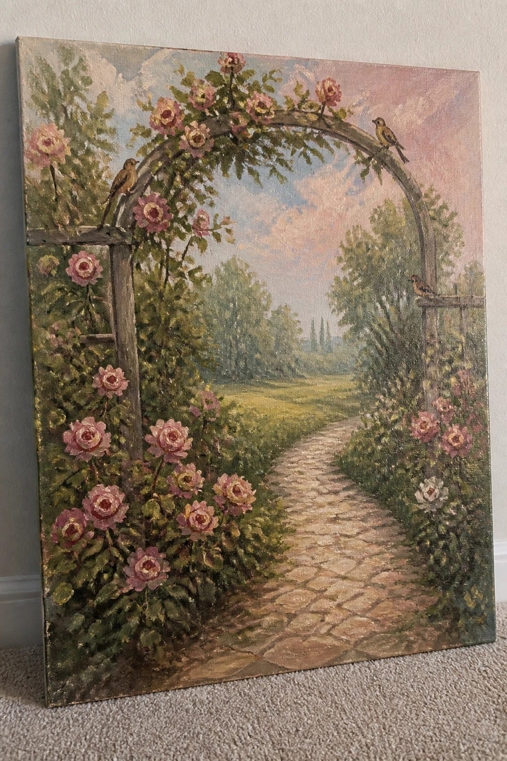 Pink rose-covered arch over cobblestone garden path with perched birds in landscape painting.