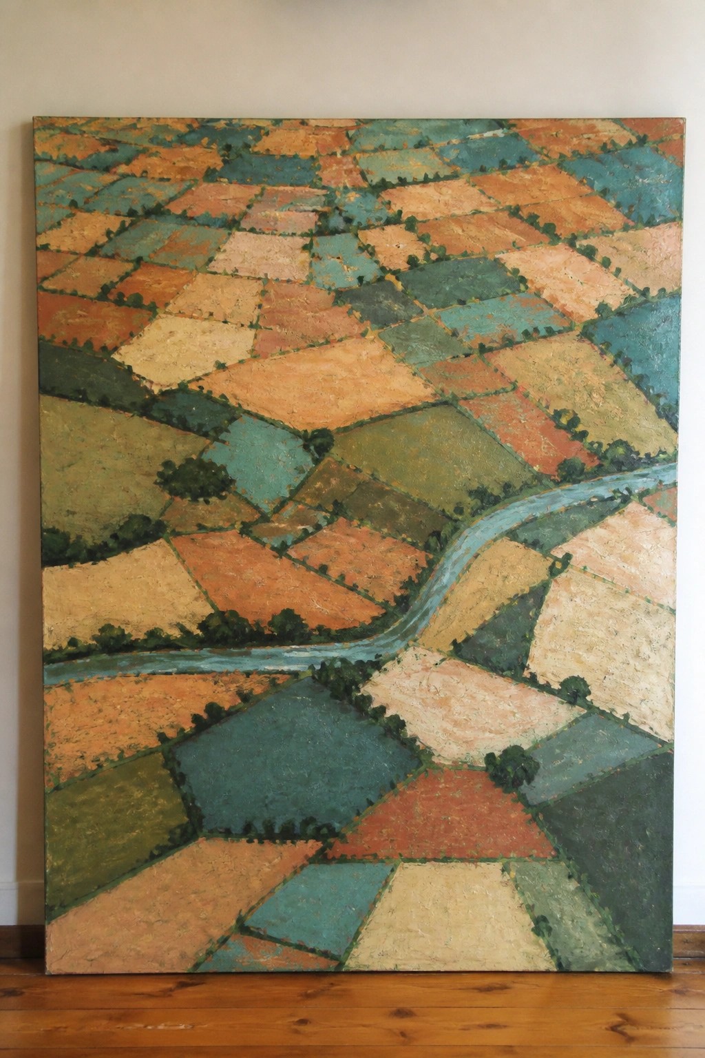 Patchwork fields in orange, teal, and green with winding blue river.