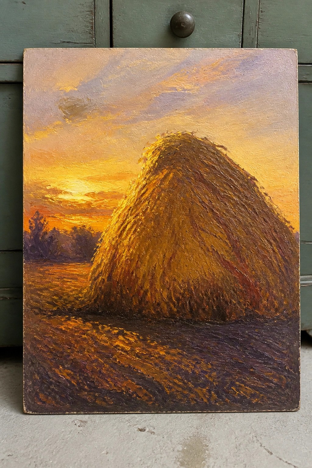 Tall haystack in field under vibrant orange-purple sunset sky with golden light