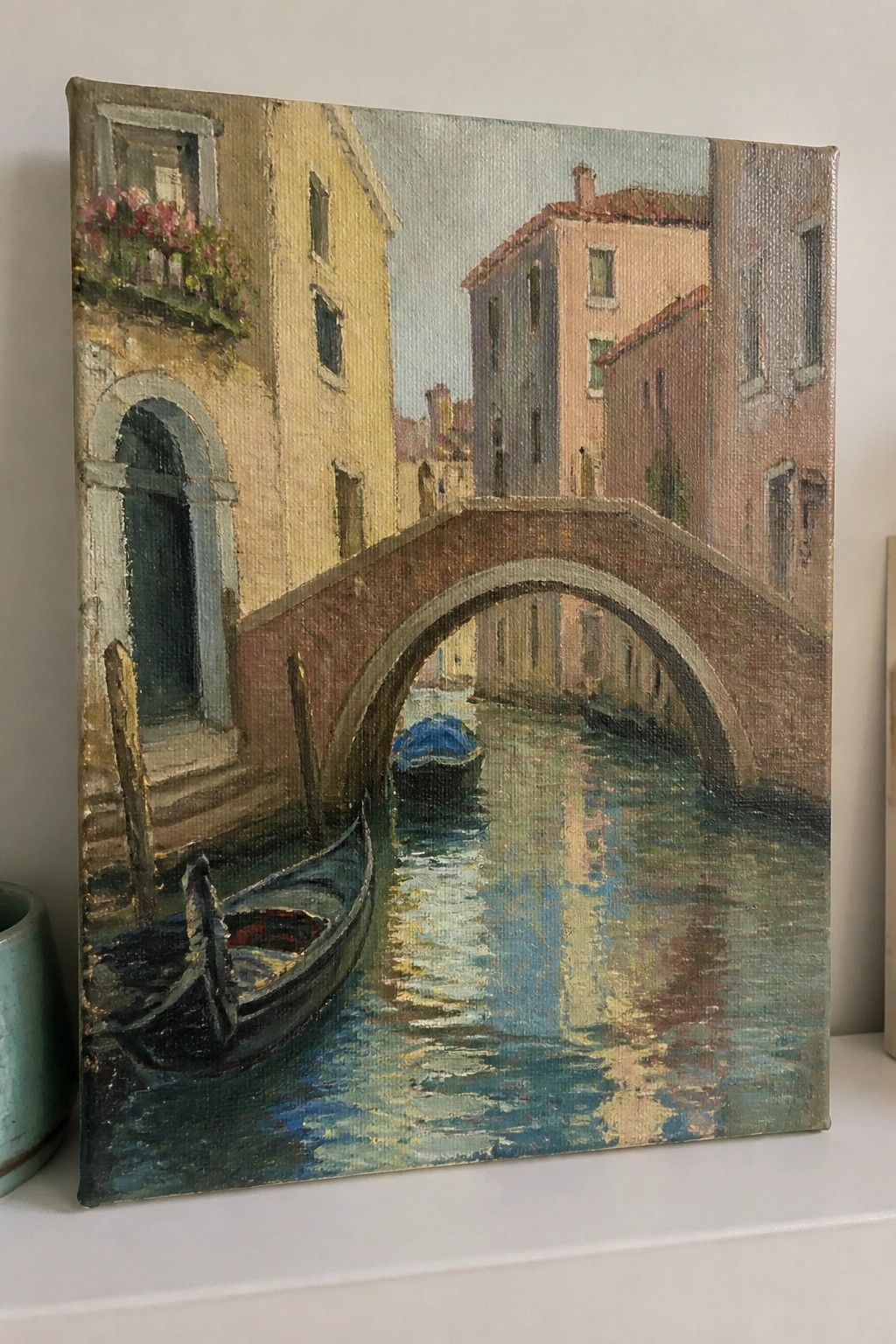 Oil painting of Venetian canal with arched brick bridge, gondolas and colorful buildings.