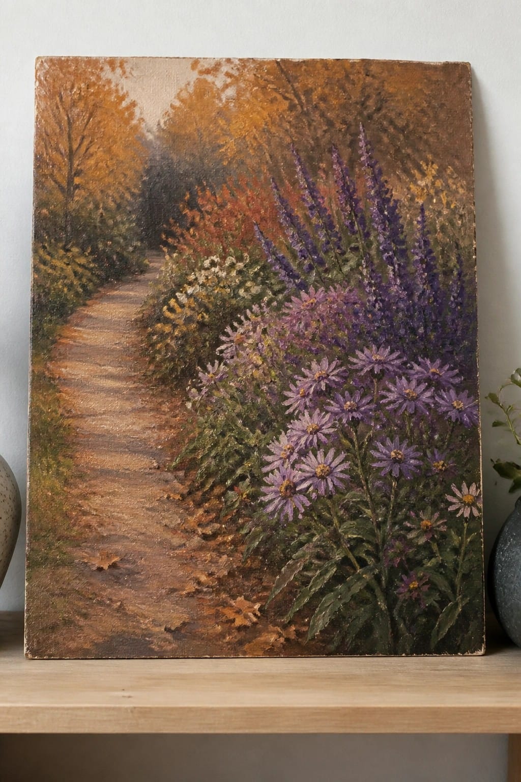 Autumn path lined with vibrant purple asters amid orange and yellow foliage.