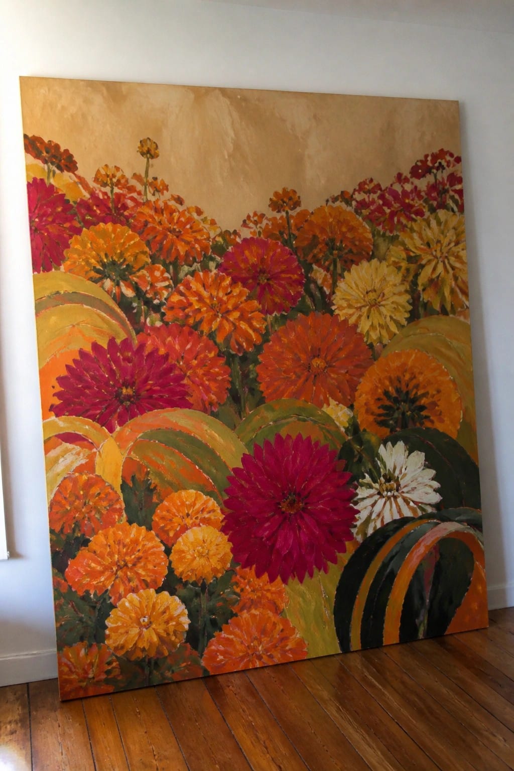 Vibrant painting of dense red orange yellow zinnias with golden textured background on wooden floor