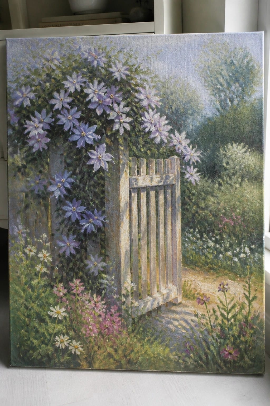 White wooden gate with purple climbing flowers beside a garden path.
