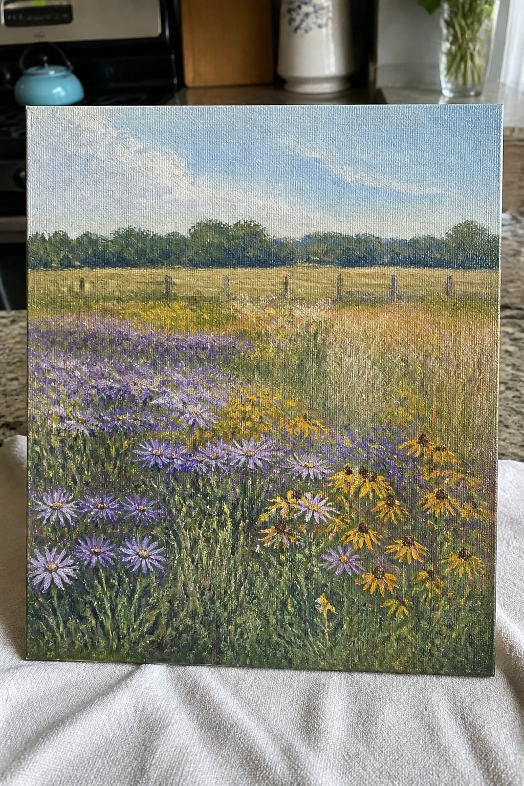 Painting of purple and yellow wildflowers in meadow with fence, trees, and blue sky