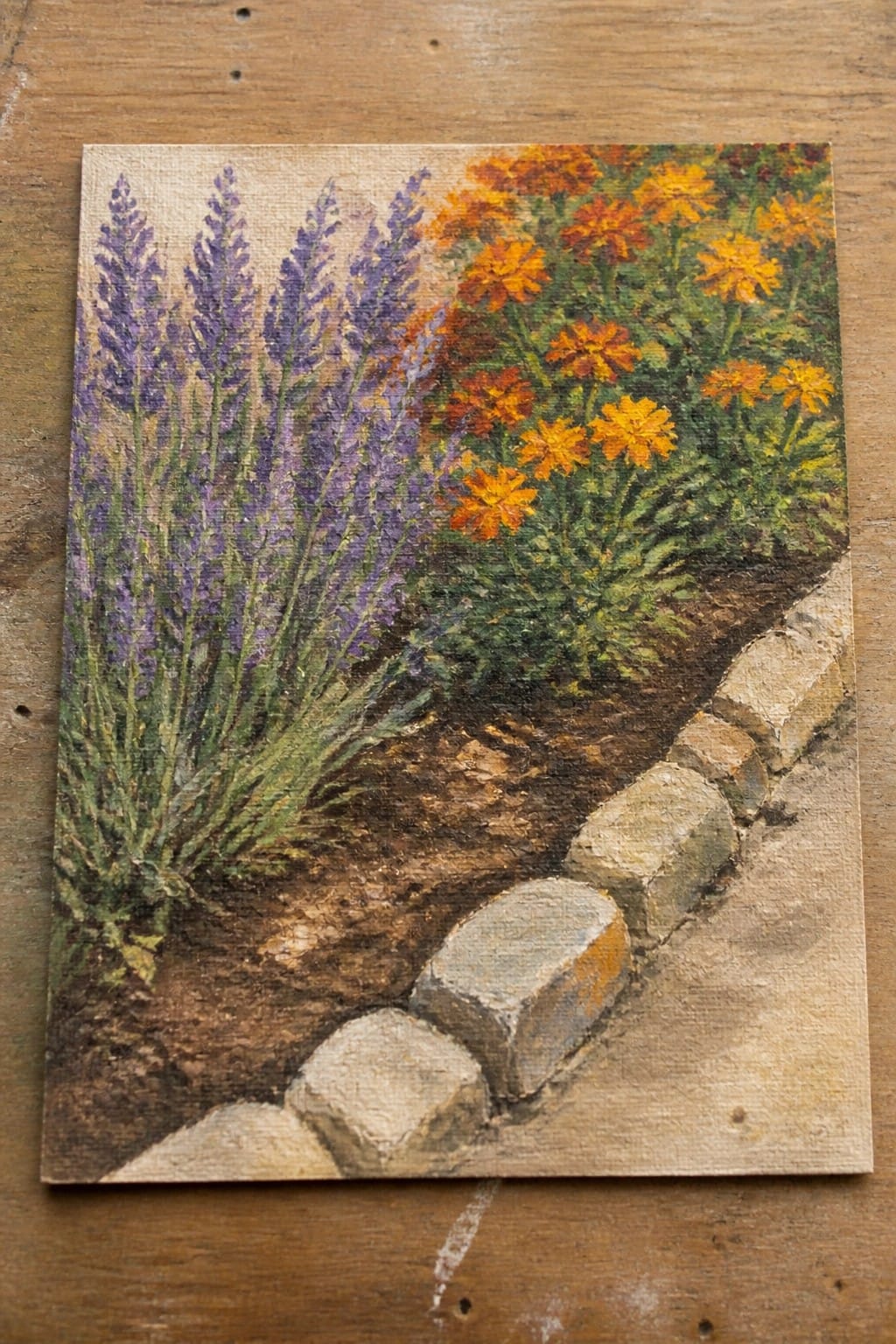 Painting of purple lavender and orange flowers beside a stone garden border.