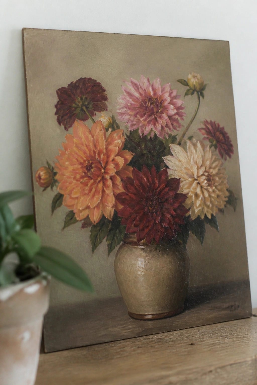 Oil painting of colorful dahlias in a beige vase on wooden table