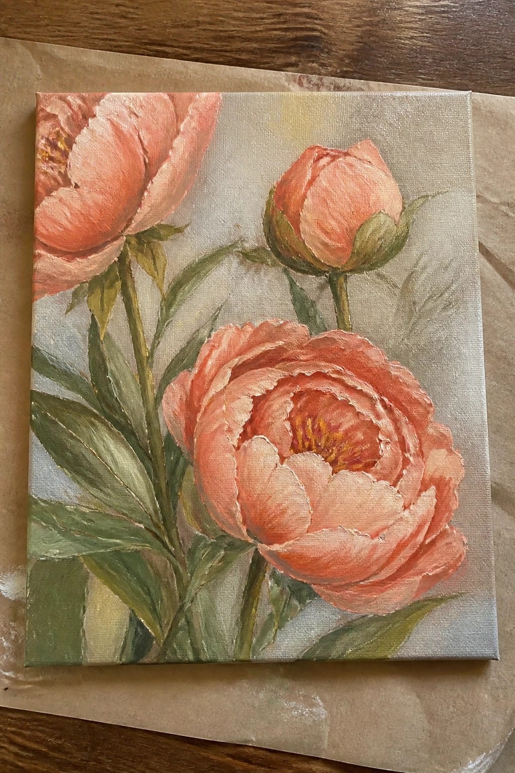 An oil painting of three coral peonies with green leaves on a light background, showing one open flower, one partial bloom, and one bud.