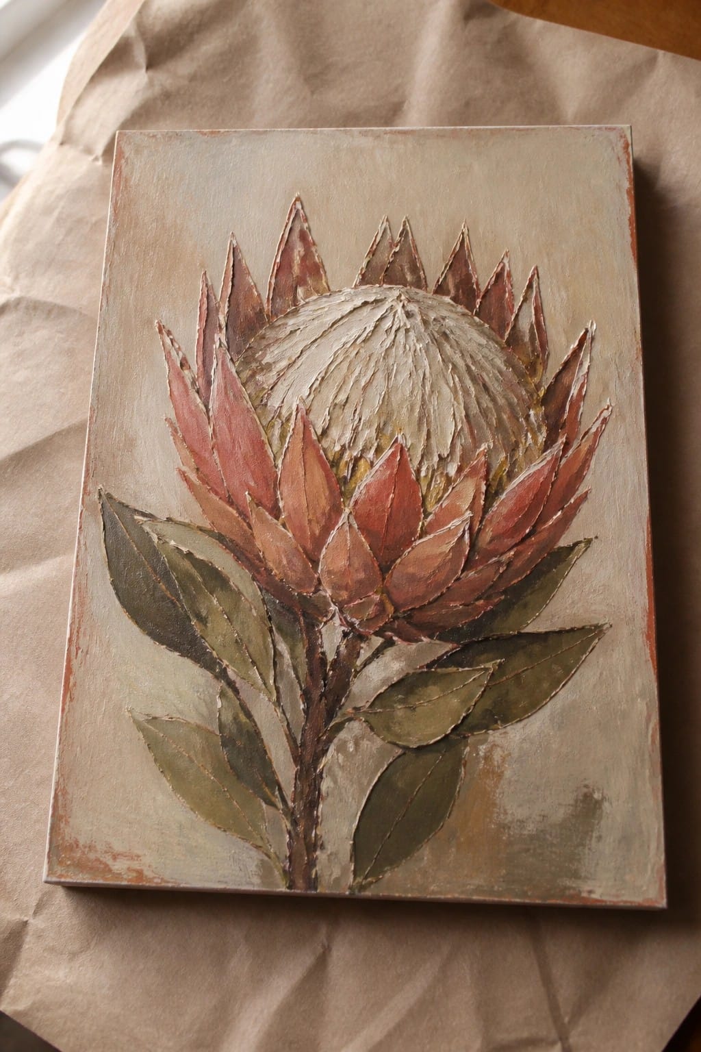 Textured painting of a protea with pinkish petals, white center, and green leaves on canvas