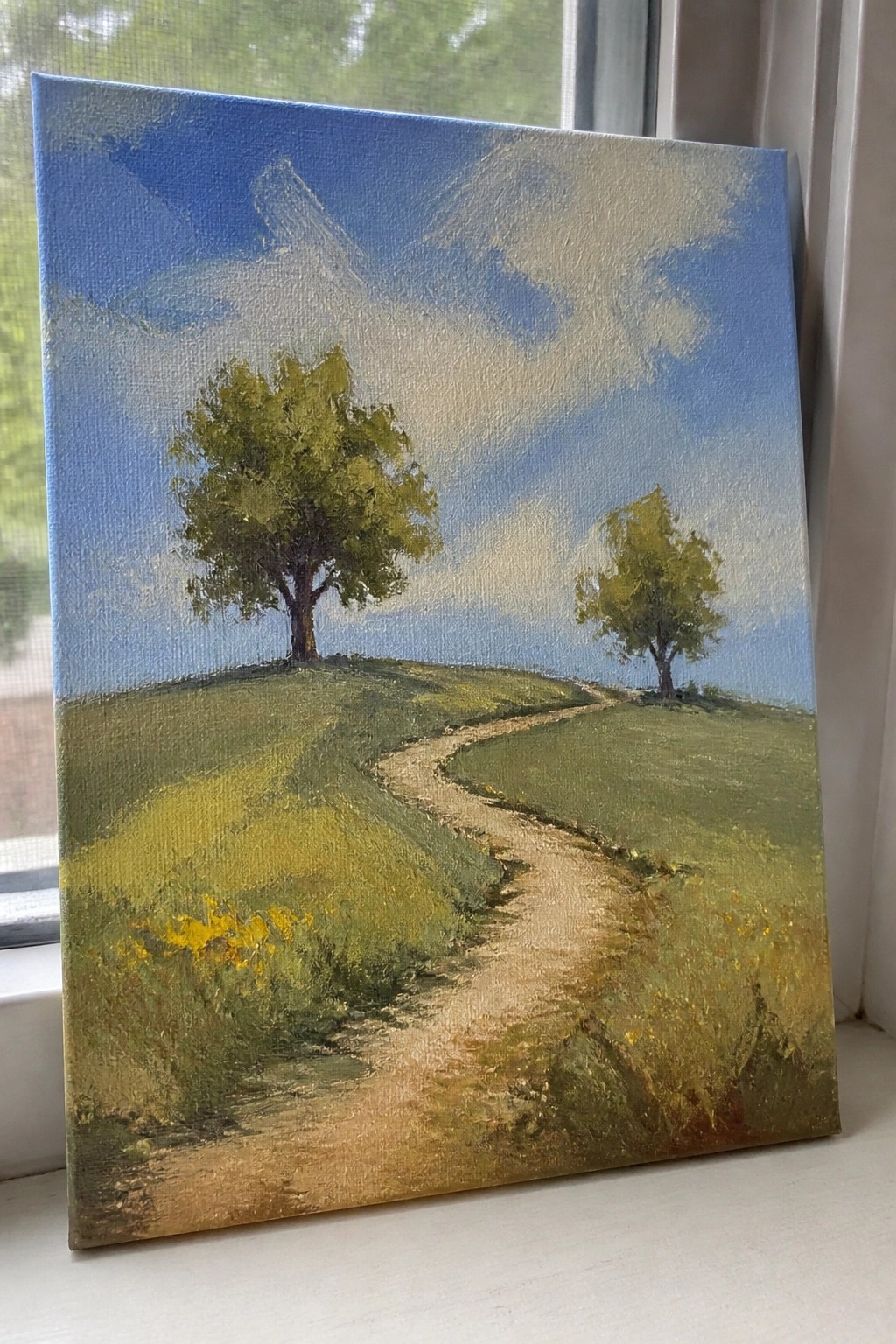 Oil painting of winding path through green hills with two trees under blue sky
