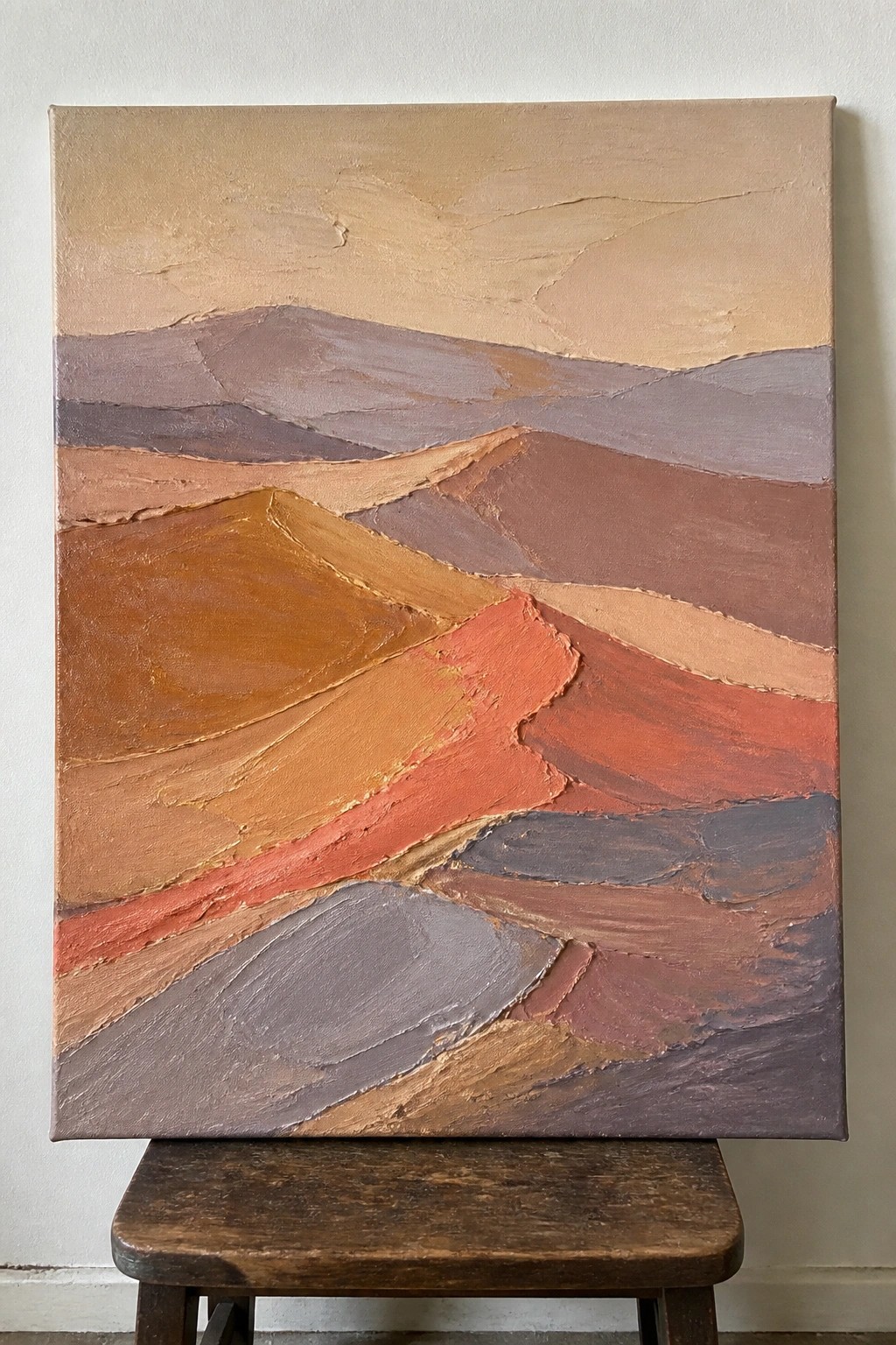 Textured abstract landscape painting with layered earth tones on wooden stool.