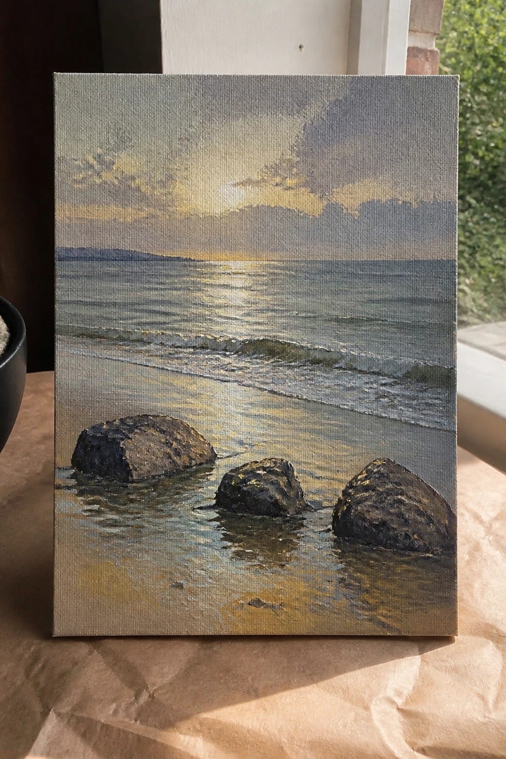 Sunset seascape painting with waves, golden light reflections, and three dark rocks in water