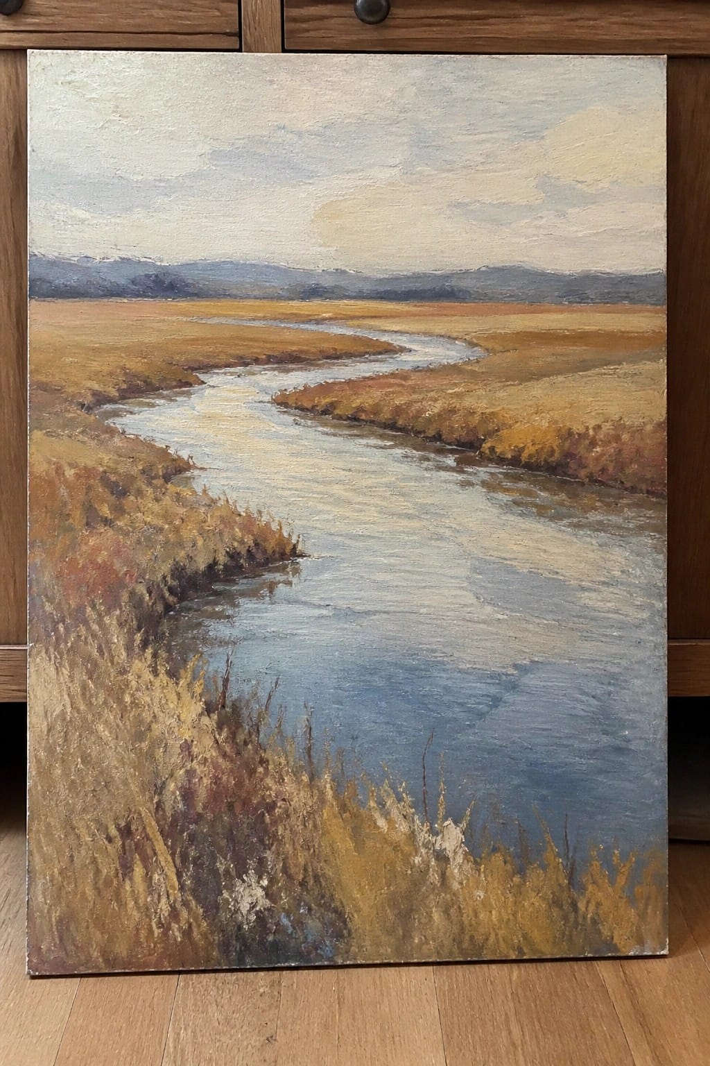 Oil painting of winding river through golden-brown fields toward distant mountains.
