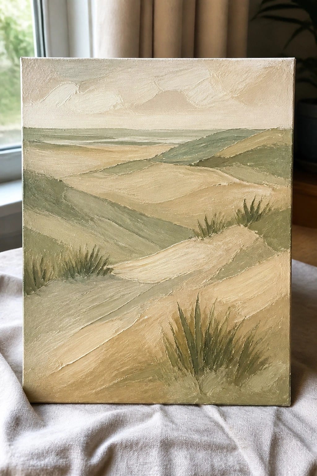 Oil painting of rolling green and beige hills with grass tufts on white cloth