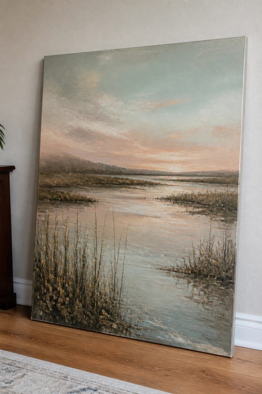 Large impressionistic painting of marsh at sunset leaning on wall