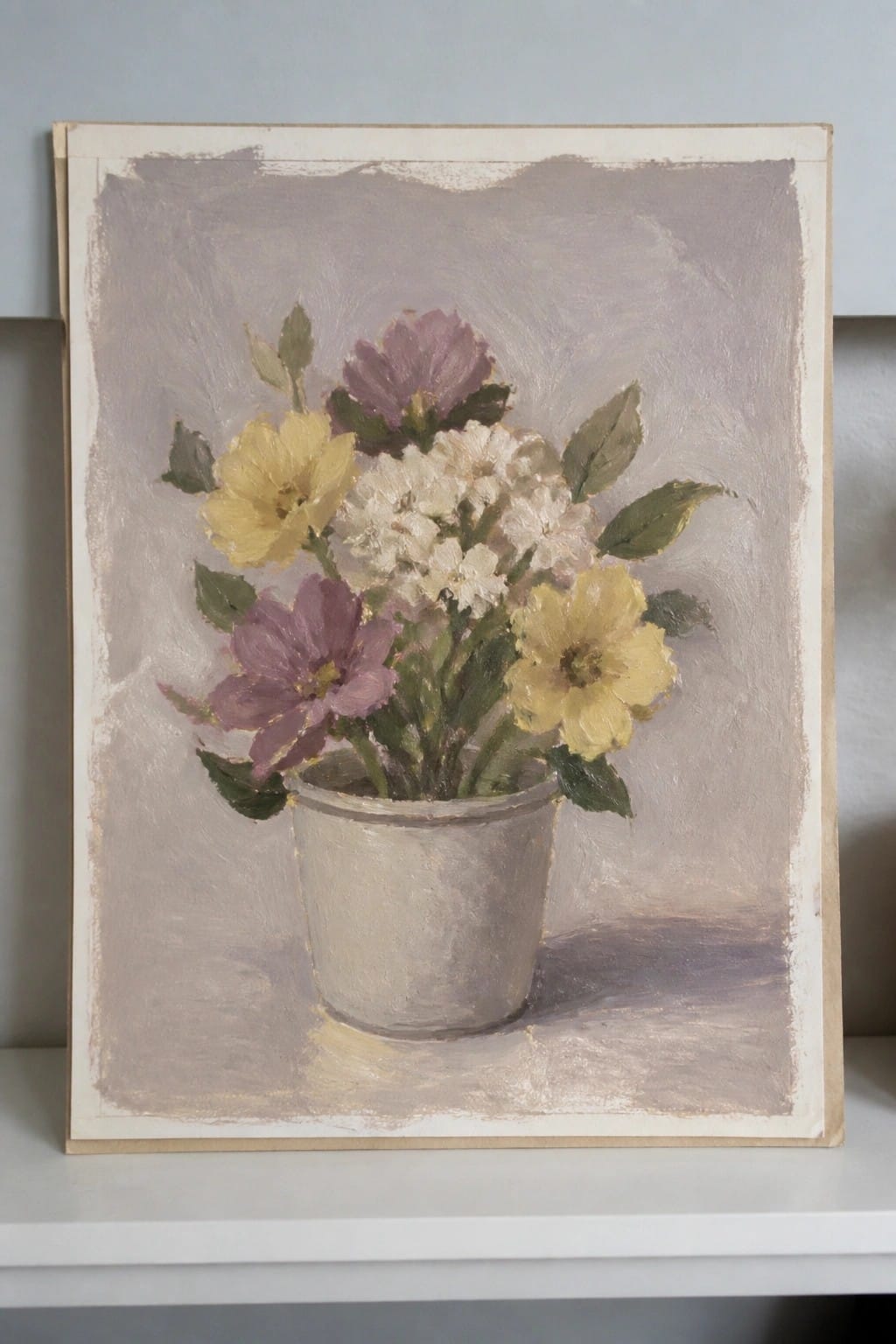 Yellow and purple flowers in a gray pot against a muted background on white surface