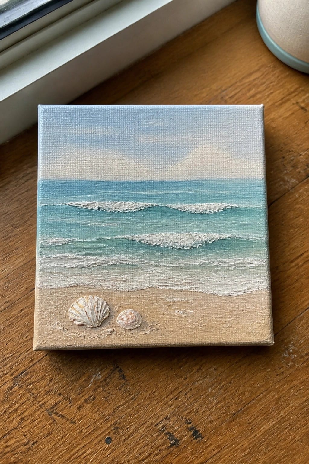 Small square canvas painting of turquoise ocean waves on sandy beach with seashells.