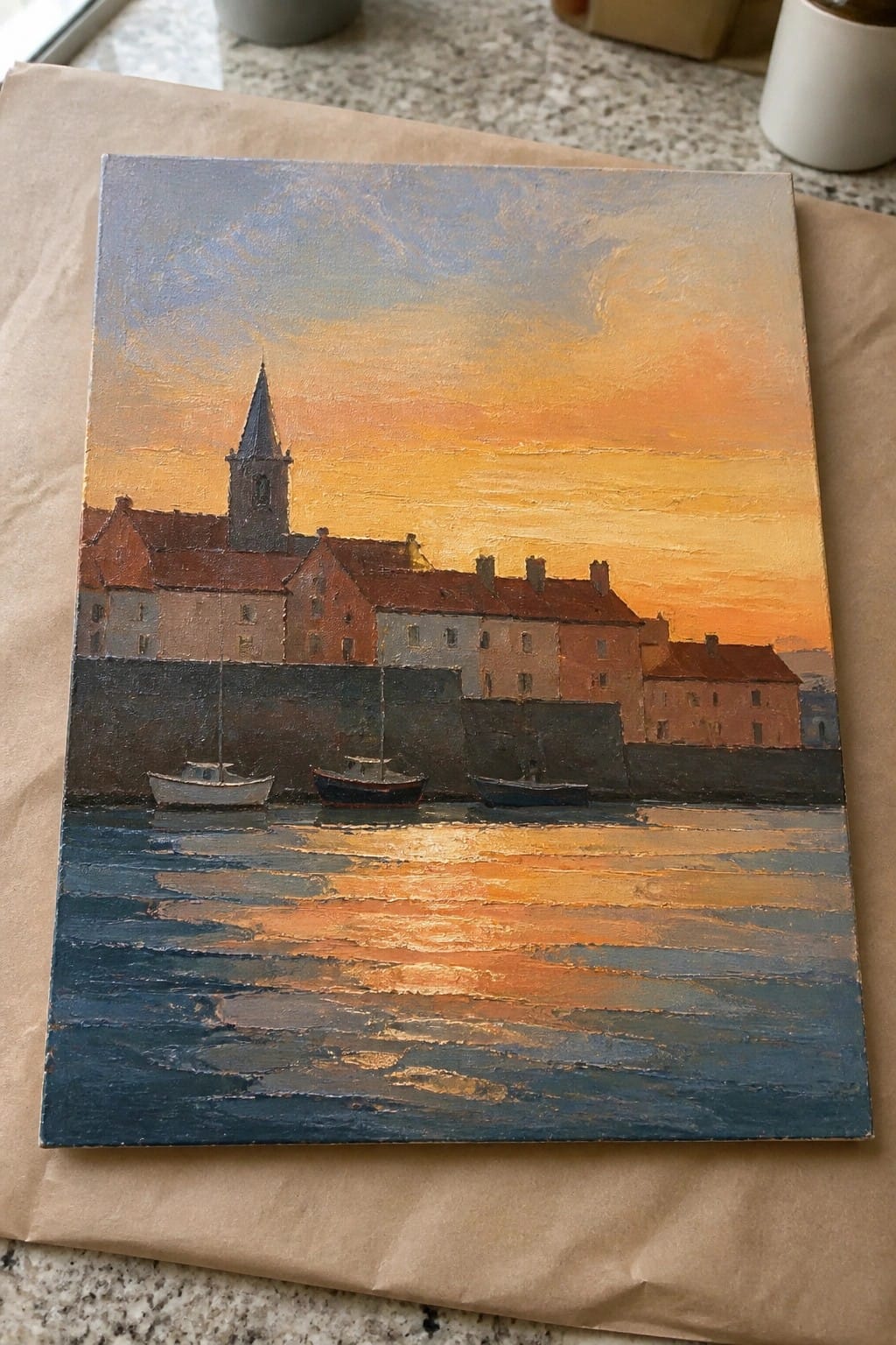 Oil painting of sunset harbor with boats, red-roofed buildings, and church steeple.