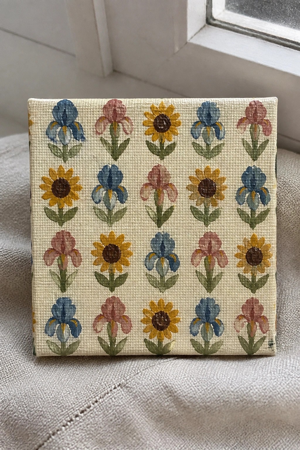 Small square canvas with rows of blue and pink irises plus yellow sunflowers on beige.