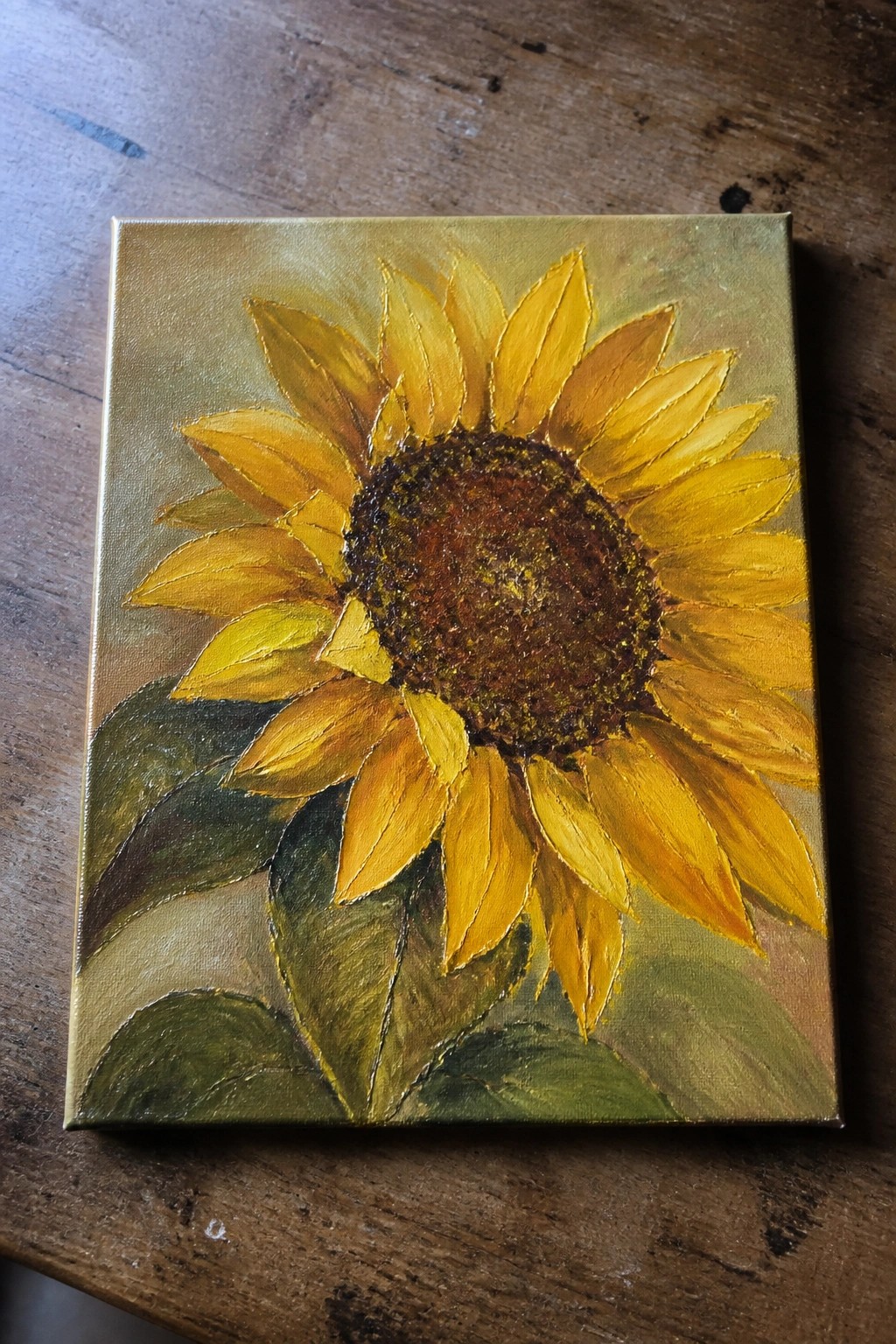 Sunflower painting with yellow petals, brown center, and green leaves on gold background