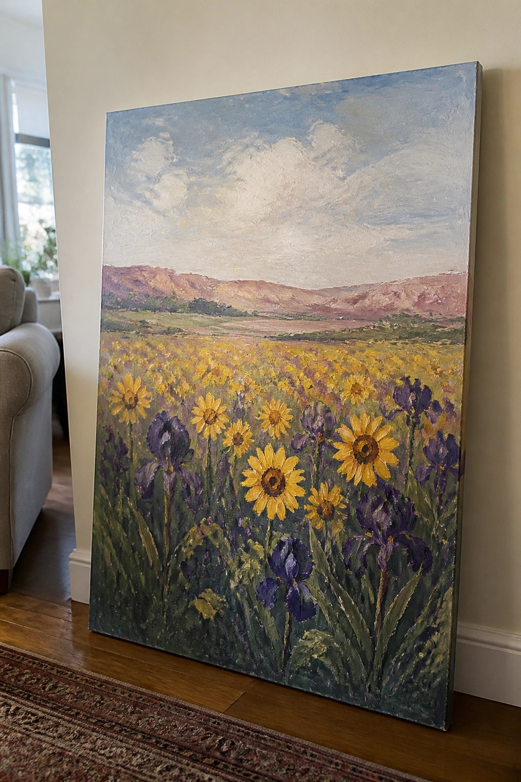 Large painting of sunflower field with purple irises and distant mountains