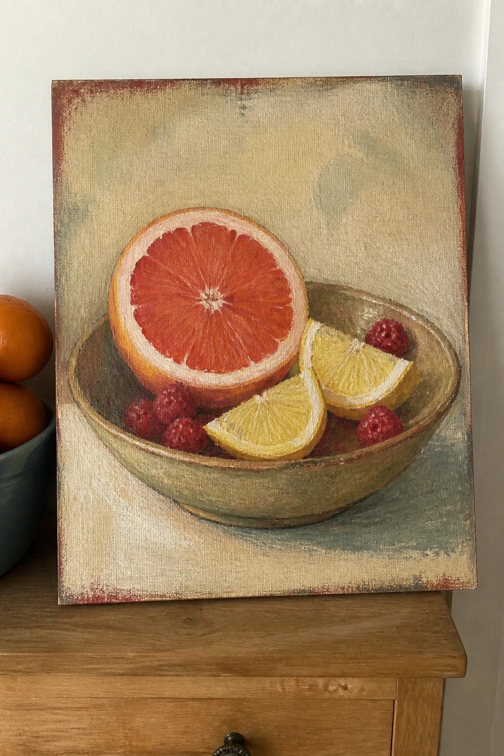 Still life painting of grapefruit, lemon slices, and raspberries in a rustic bowl.
