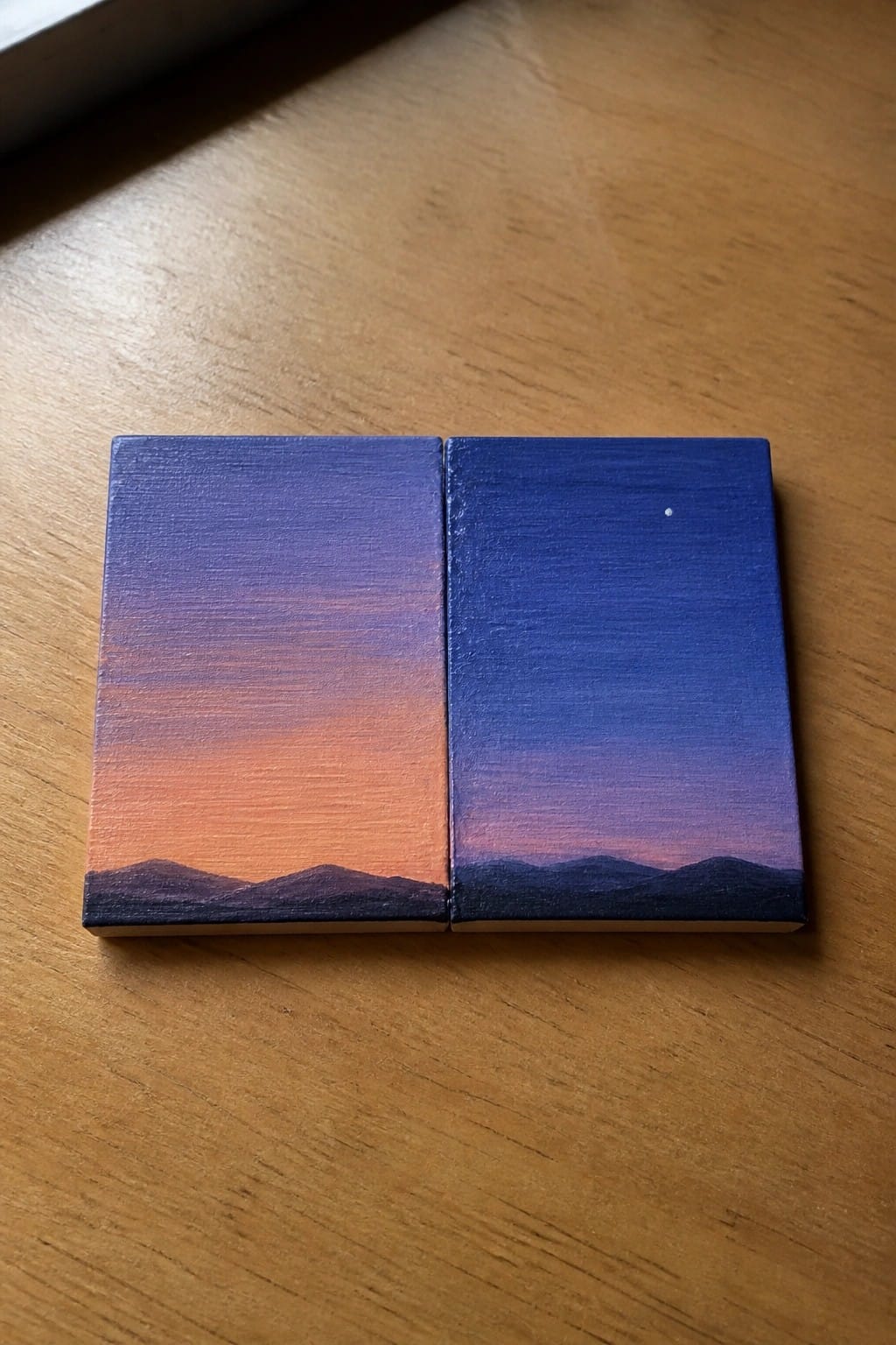 Two miniature canvases showing gradient sunset sky over dark mountain silhouettes with a star.