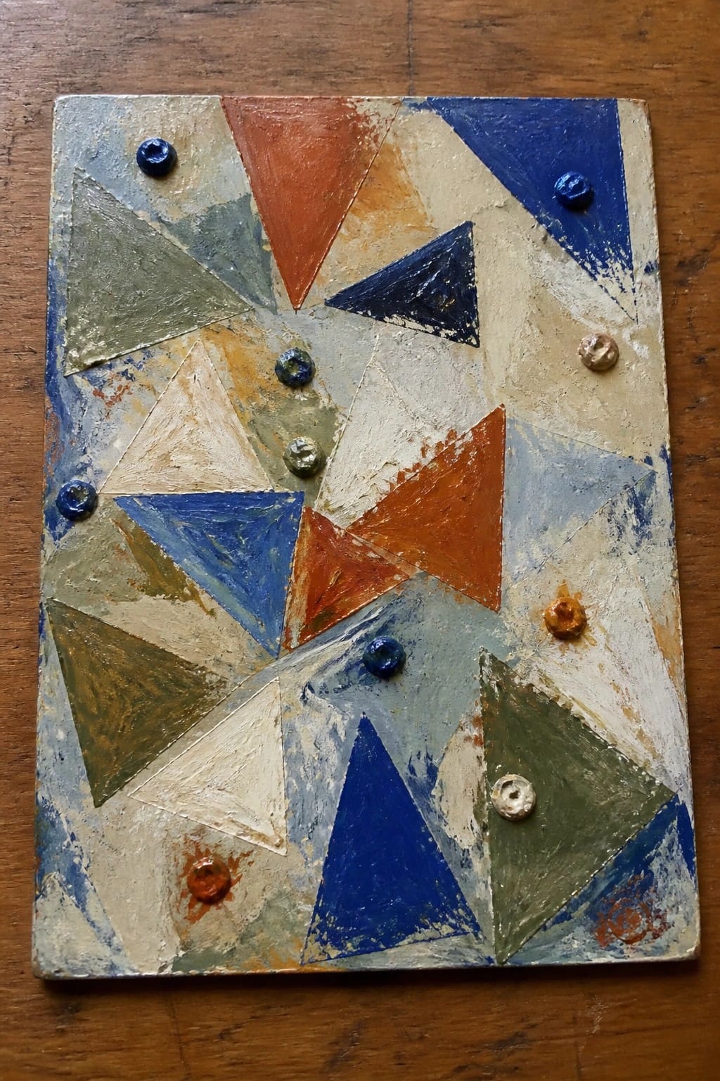 Abstract geometric painting with multicolored triangles and raised circular accents