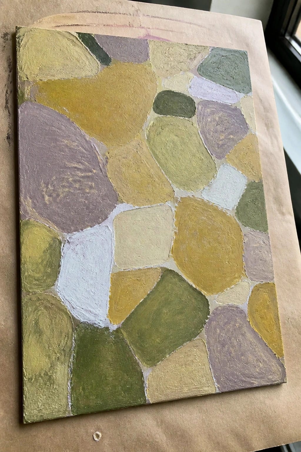 Abstract canvas painting with irregular pebble-like shapes in earthy green, yellow, and purple tones